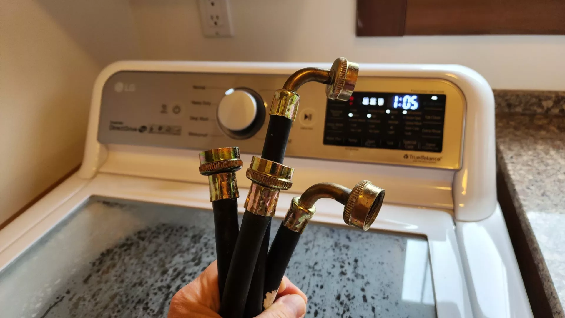 Rubber laundry hoses in front of a washing machine.
